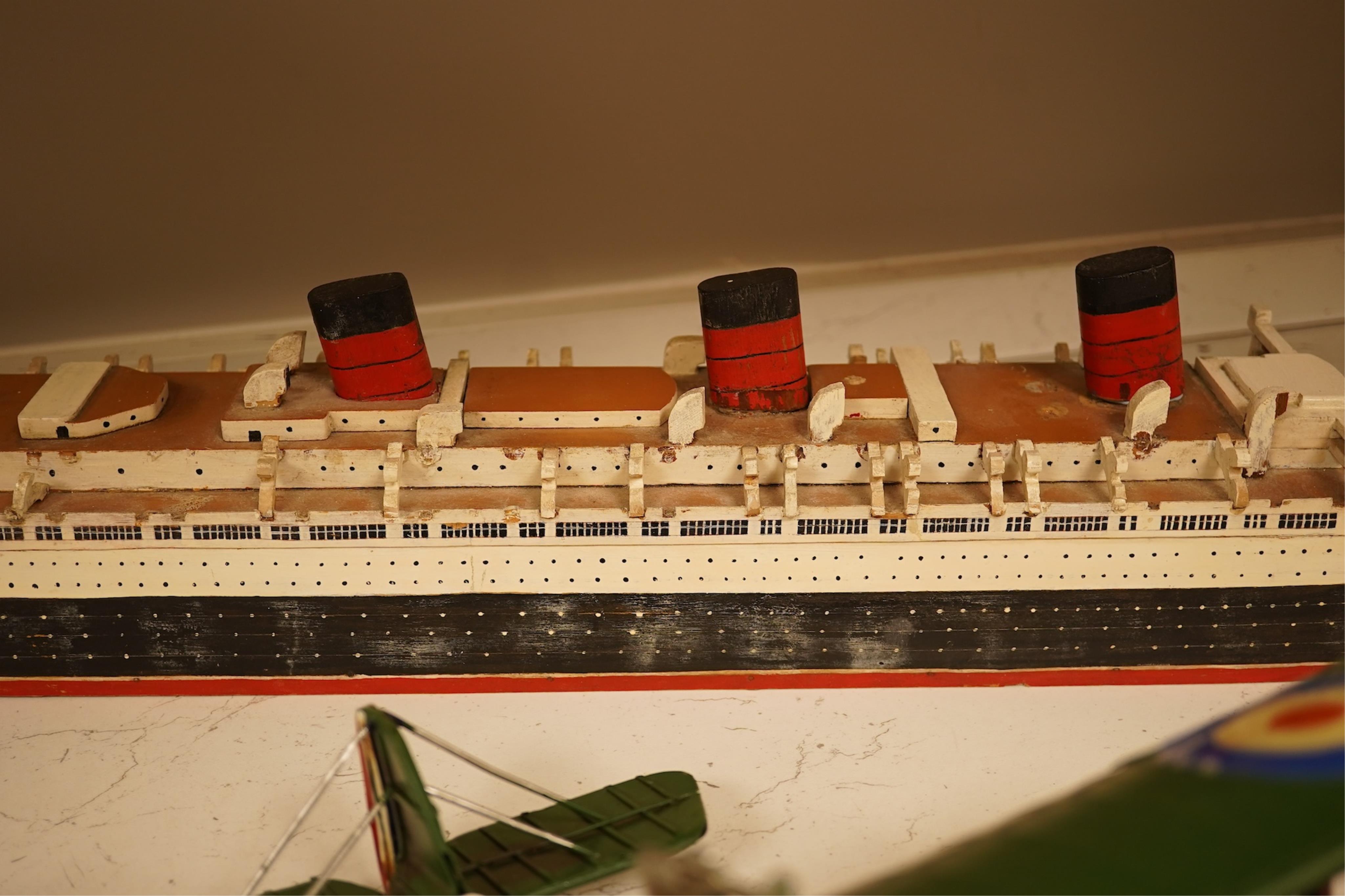 Five decorative metal models of military aircraft, including two Supermarine Spitfires, two First World War, British bi-planes, a German Albatros D.III bi-plane, and a wooden model of RMS Queen Mary, hull 77cm long